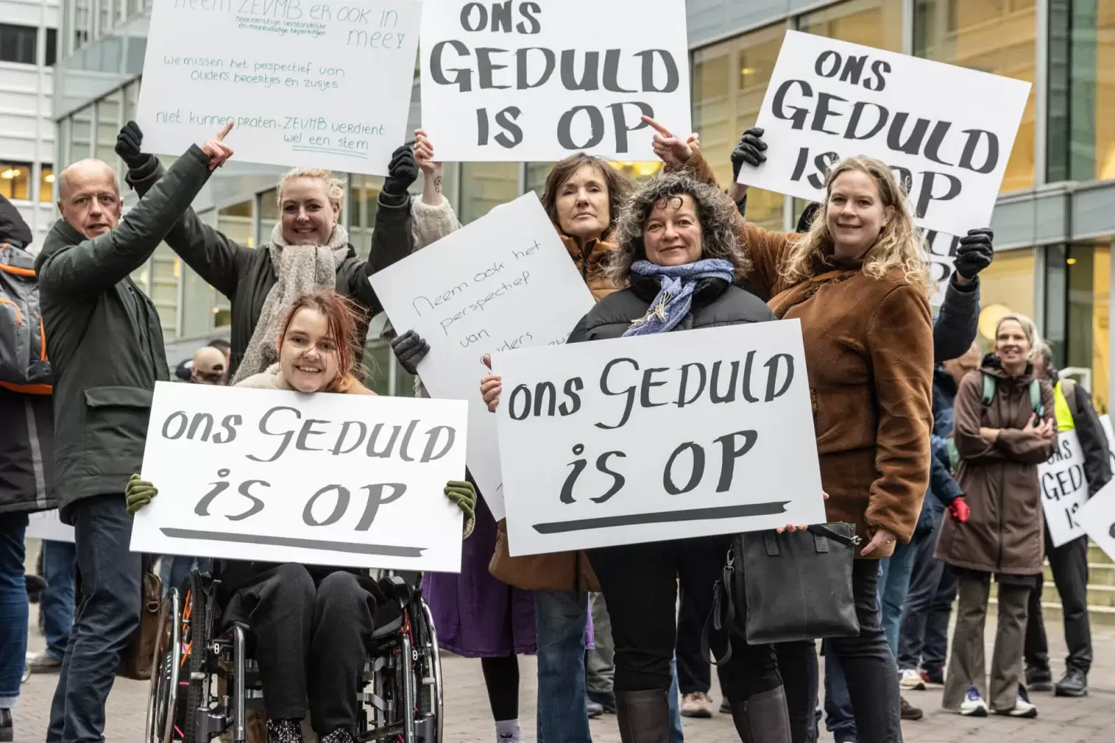 Een groep mensen staat buiten bij elkaar. Ze hebben protestborden vast met de tekst: ons geduld is op. 