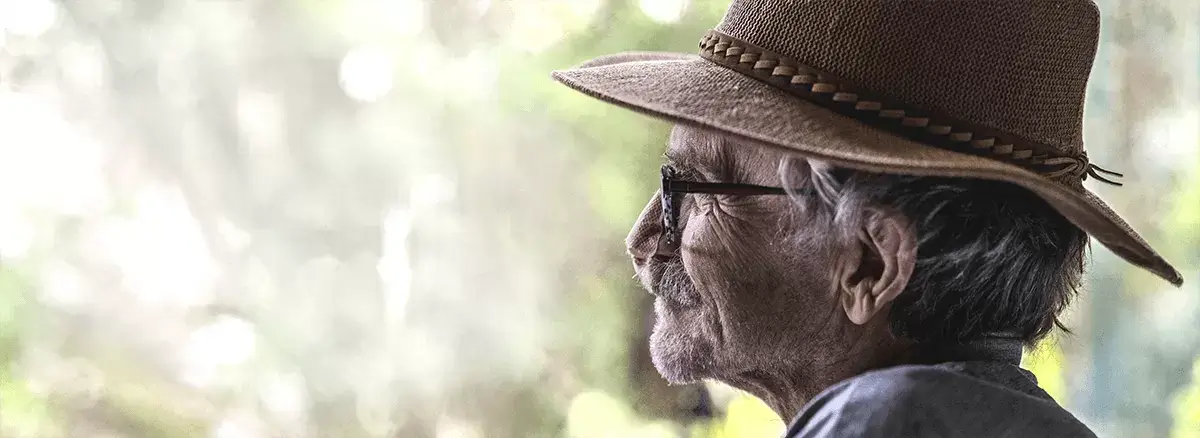 Portret van Jan Troost. Hij draagt een hoed en kijkt in de verte. Op de achtergrond zijn bomen te zien.