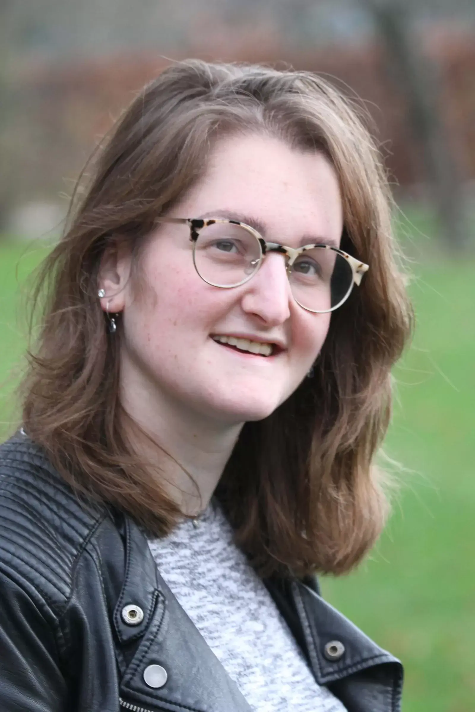 Portret van Daniëlle. Ze heeft lang donkerbruin haar, draagt een bruine bril en een zwart leren jack.